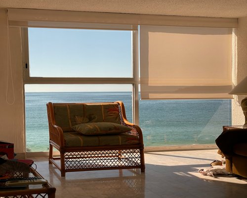 Large window filtering bright afternoon sunlight through thin curtains into an organized Mexican apartment living room